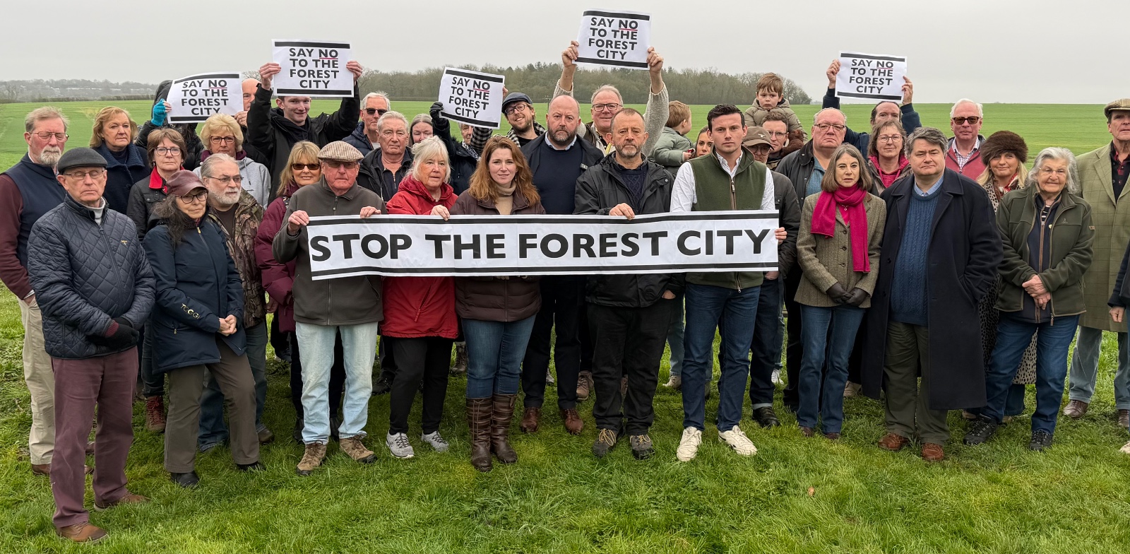 Residents of West Suffolk villages gathered in a field holding a 'Stop the Forest City' banner